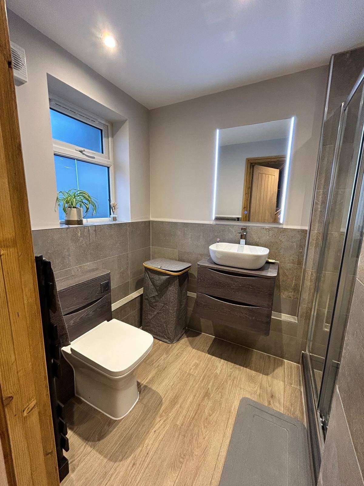 Grey tile bathroom with warm floor and LED mirror