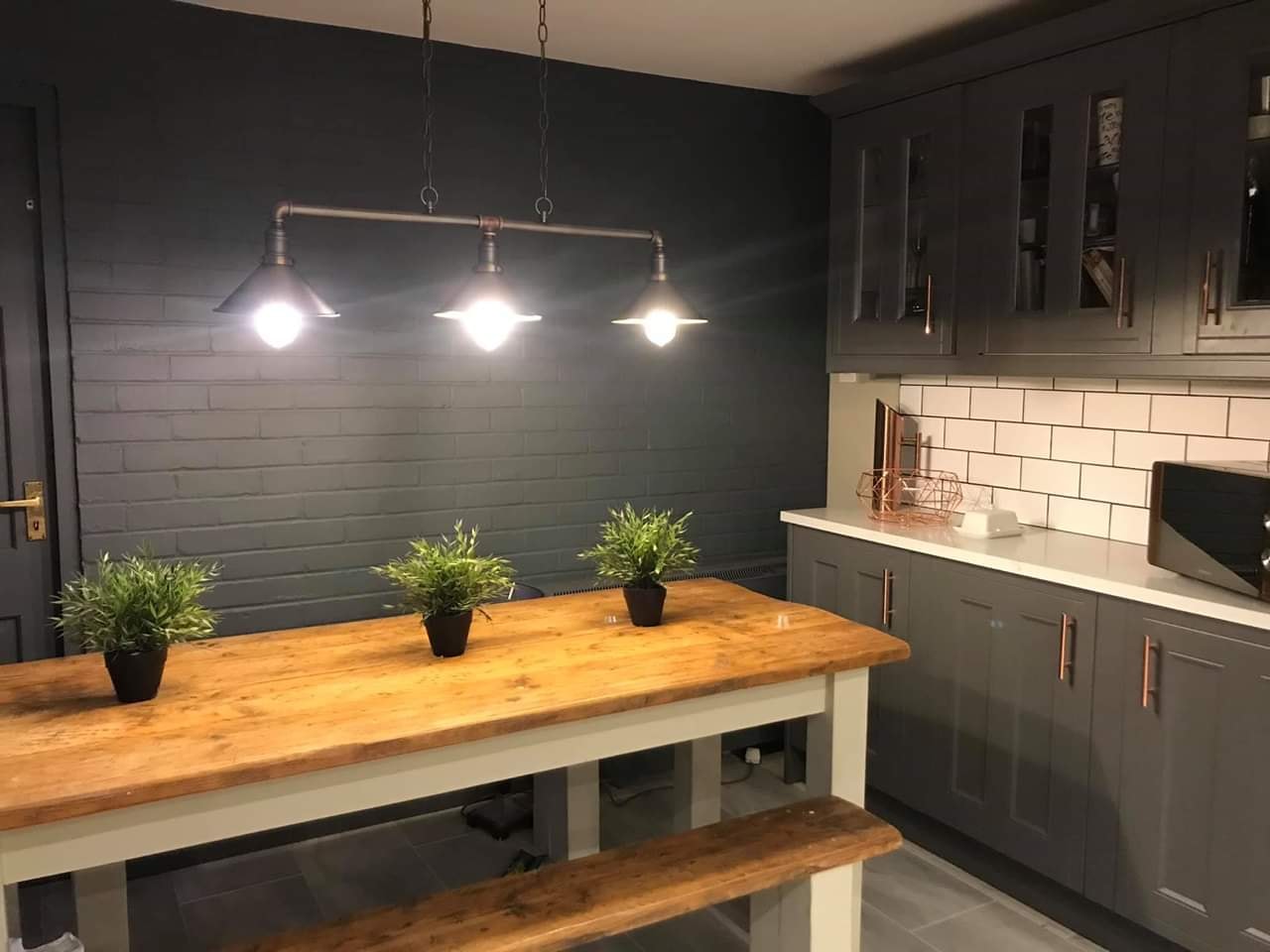 Dark shaker kitchen with copper handles and rustic table
